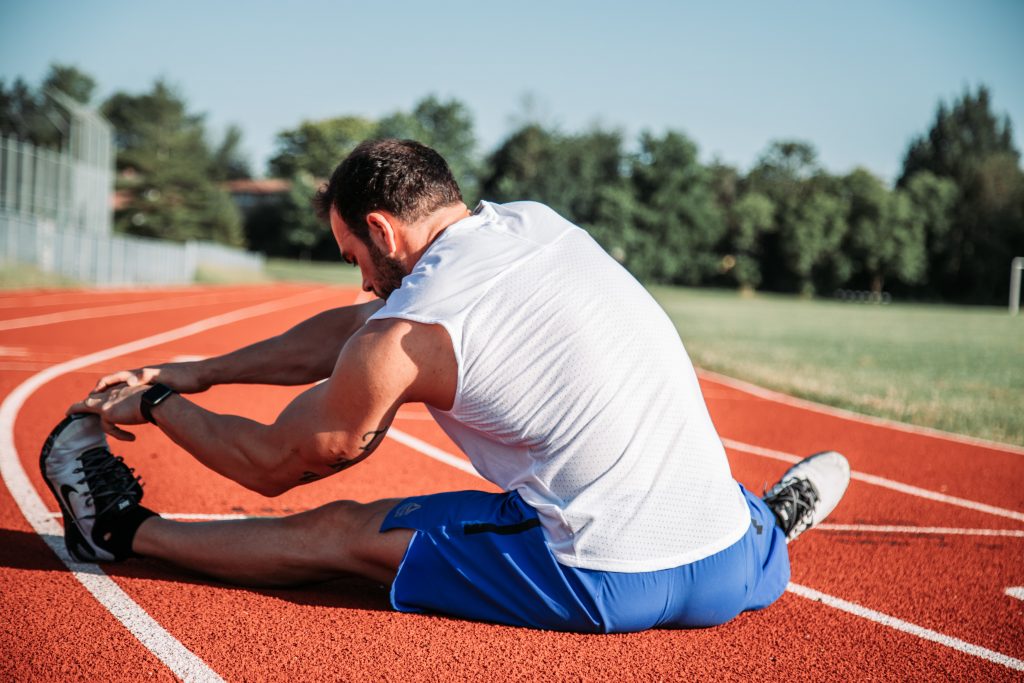man stretching on the floor of a running track