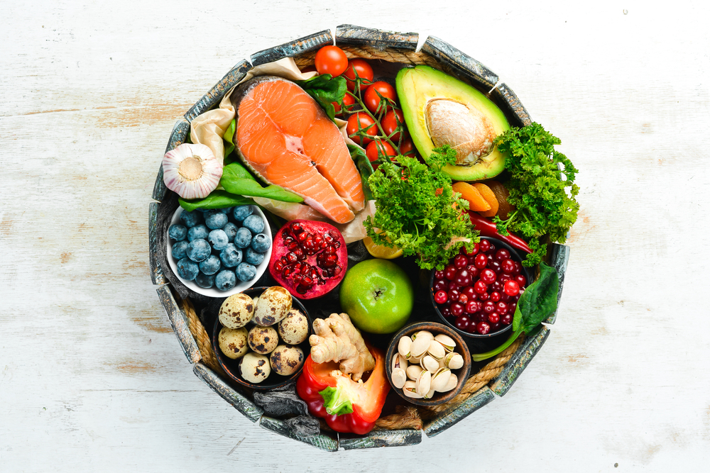 a bowl of healthy food containing fruit, vegetables, nuts and fish