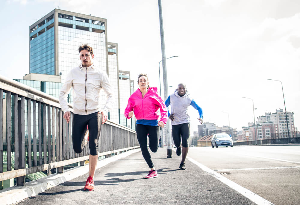 three marathon runners running through a city